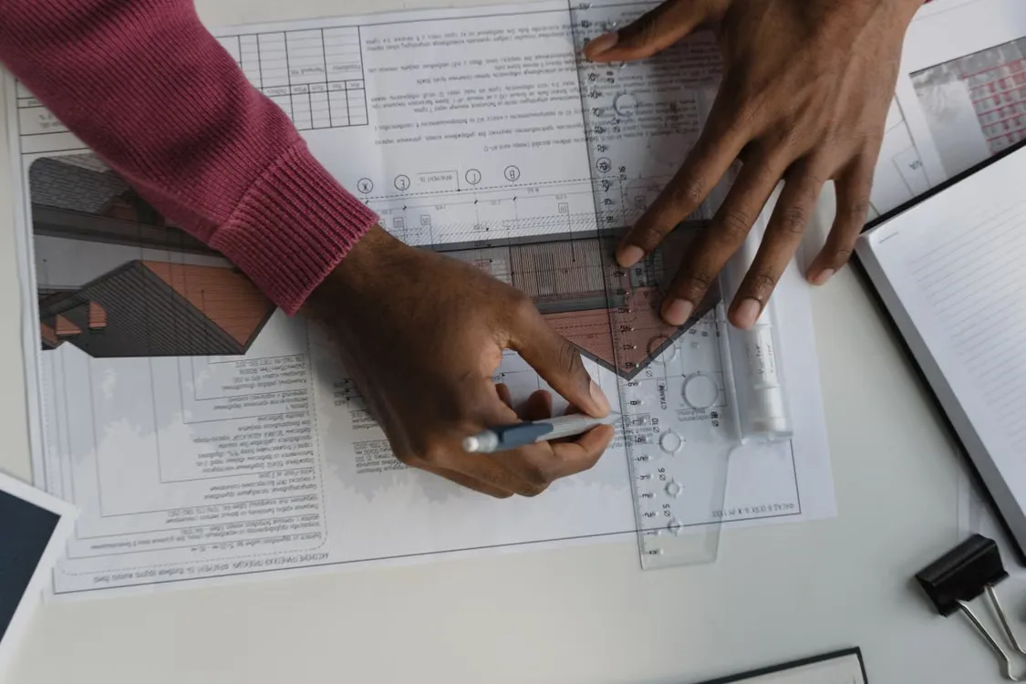 architect measuring and sketching a building plan with a ruler
