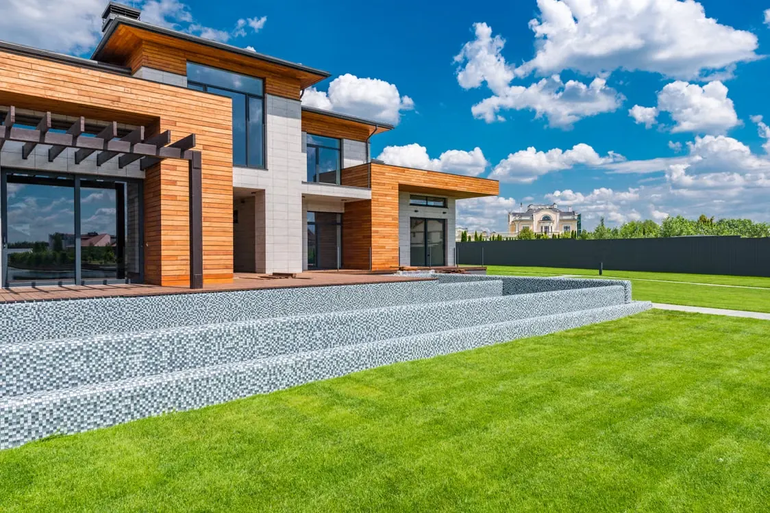Modern white-and-wood home with a lawn and fence.
