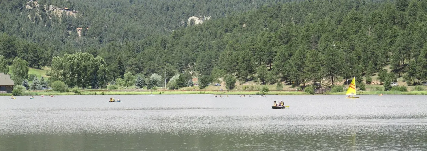 Boaters on Evergreen Lake beneath wooded Colorado foothills