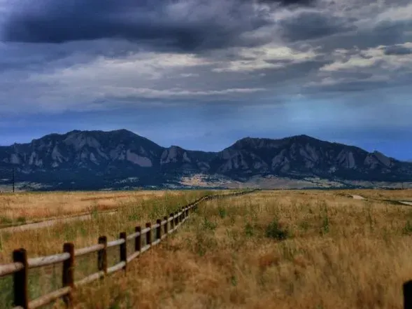 Fenceline across open grassland with Front Range mountains near Louisville, Colorado